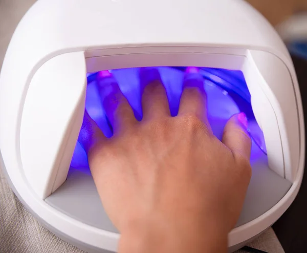 Human hand in UV lamp. Woman Drying Nails in UV Lamp.