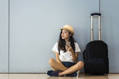 Havaalanı genç kadın yolcu terminal Salonu onu uçuş için bekleyen oturuyor ve akıllı telefon