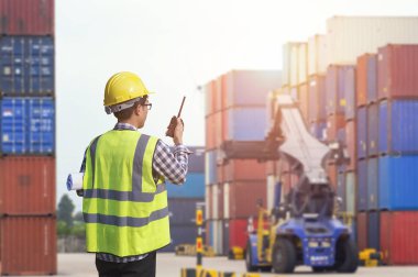 Ustabaşı kontrolü, kargo nakliye gemisinden ithal etmek için konteynır kutusu yüklüyor..