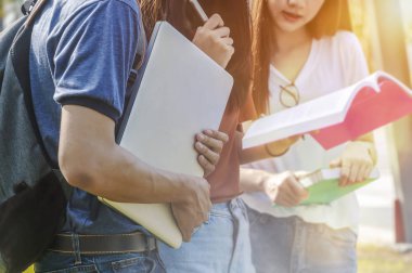 Asya Grup Eğitim Üniversitesi Yüksek Okulu kampüs grup okul klasörlerle mutlu genç öğrenci dizüstü bilgisayarda tablet ile gülümseyen kitap çalışma okuma.