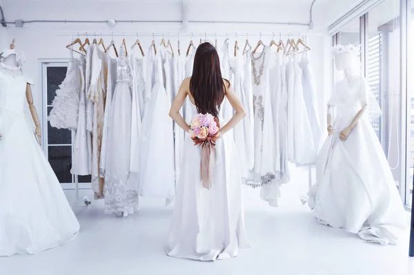 Kind of bride from the back, Female in trying wedding dress in a shop.