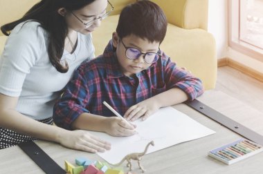 Mutlu bir aile. Anne ve oğlu çizim ve evde otururken gülümseyen.