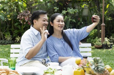 Kıdemli çift öğleden sonra çay içme ve almak a fotoğraf içinde bahçe dinlenmek kavramı - görüntü.