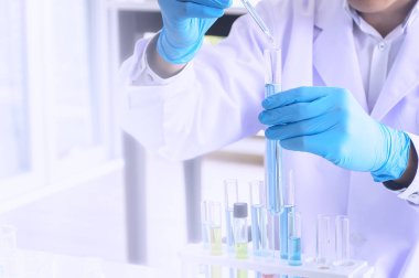 Scientist holding sampling oil or chemical liquid in flask with lab glassware in laboratory background, science or medical research and development concept - Image
