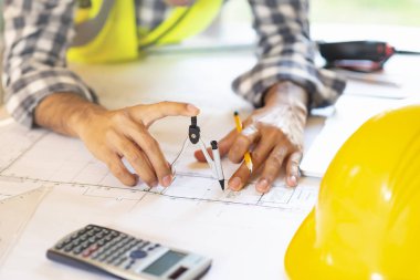 Mimar blueprint.engineer Müfettiş işyerinde - mimari proje, planları, cetvel, hesap makinesi, laptop ve bölücü pusula üzerinde çalışıyor. İnşaat kavramı. Mühendislik araçları, seçici odak