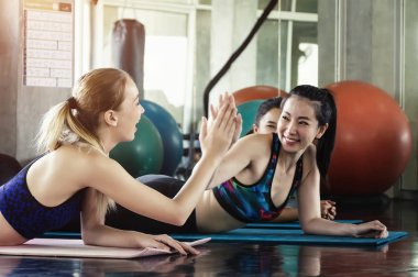 Gençlerin grup yoga dersi, kadınlar bir spor salonunda kendi yoga sınıf sırasında rahatlatıcı pratik pratik sportif çekici.