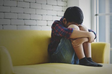 Küçük Asyalı çocuk üzgün ve depresyonda oturma odasında sonraki 