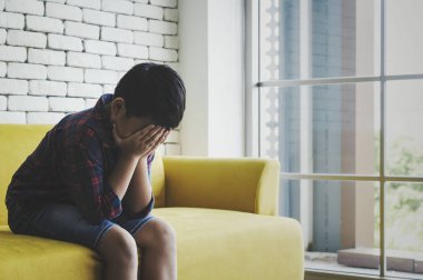 Küçük Asyalı çocuk üzgün ve depresyonda oturma odasında sonraki 