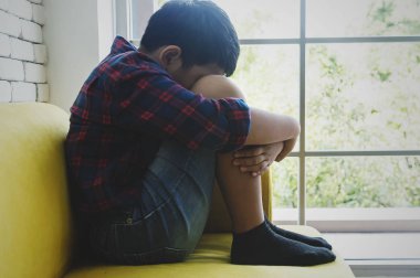 Küçük Asyalı çocuk üzgün ve depresyonda oturma odasında sonraki 