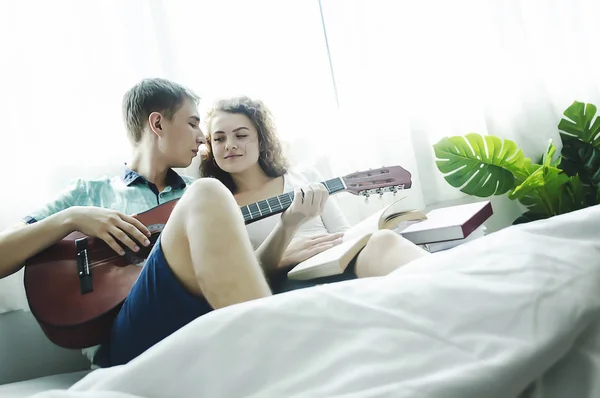 Romántica pareja joven tocando la guitarra en la cama juntos . — Foto de Stock