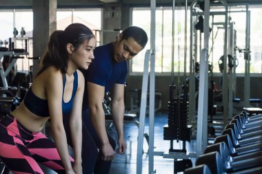 Modern spor salonunda çömelme yapan çekici genç atletik kız.