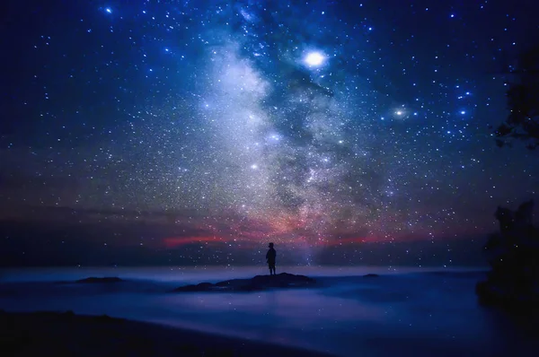 Sternenhimmel über Meer und Strand mit Menschensilhouette. Der Mensch lizenzfreie Stockbilder