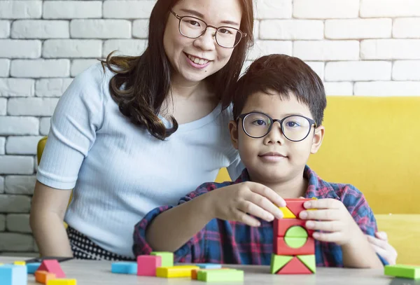 Young mummy and her kid son play with cubes toys.