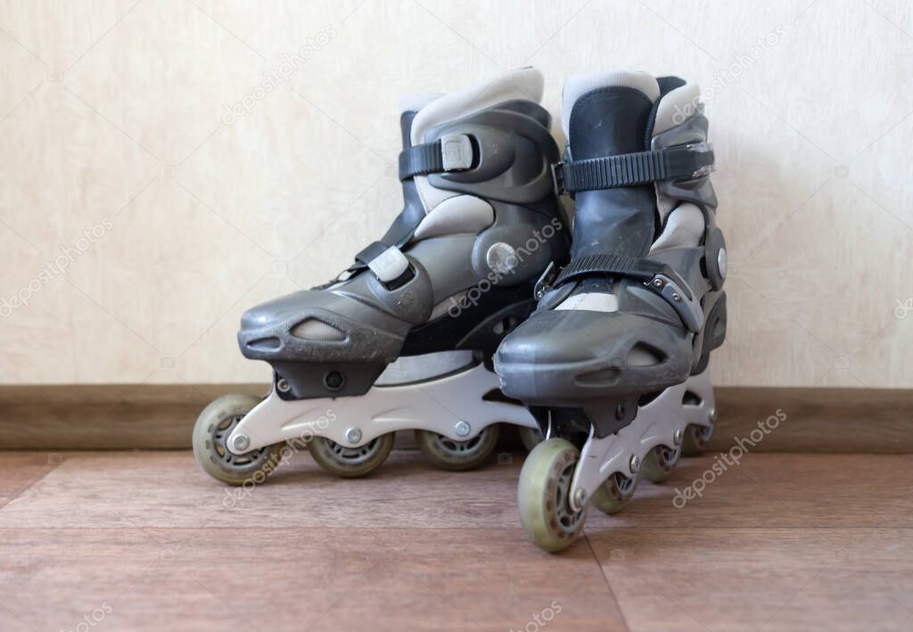 Mens old worn out roller skates on white wall background at home