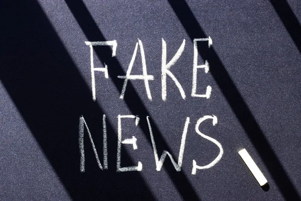 Fake news writing in chalk on a blackboard. false news, information fraud to intimidate the crowd