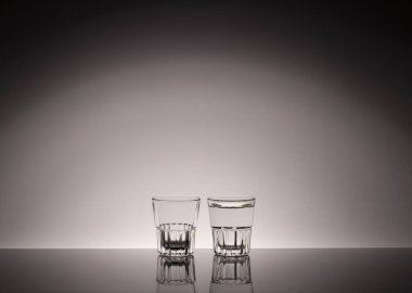 Güzel bir arka planda alkol için boş cam bardaklar. Votka ya da alkol reklamının siyah beyaz fotoğrafı. Cam atölyesi