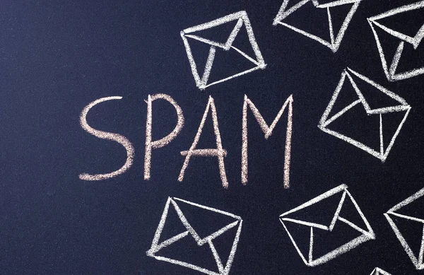 the word spam and mail envelopes drawn in white on a black Board. the concept of fighting spam on email