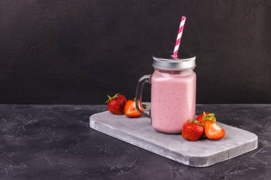 Koyu, yıpranmış bir yüzeye çilekli pembe yaz içeceği serinletici. Kokteylli olgun kırmızı çilekler.