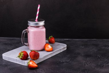 Koyu, yıpranmış bir yüzeye çilekli pembe yaz içeceği serinletici. Kokteylli olgun kırmızı çilekler.