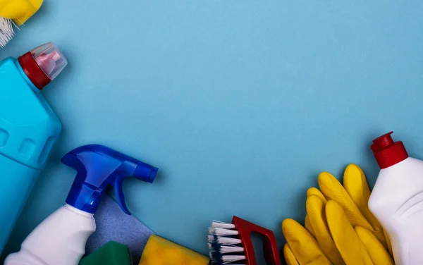 cleaning products in plastic bottles, rubber gloves with a sponge on a blue background, top view. the concept of clean house and premises cleaning