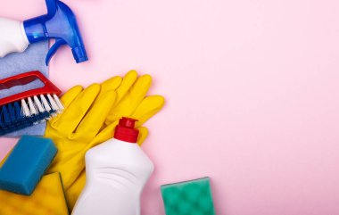 Pastel pembe arka planda ev temizlik seti, yazı için alan, üst görünüm. Odadaki temizliği sürdürme konsepti