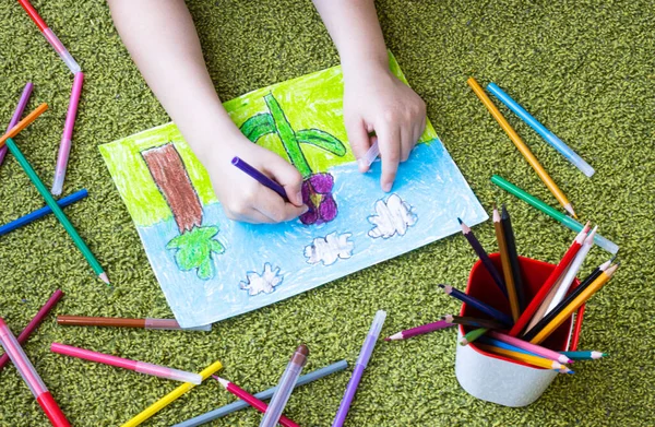 The child draws with colored markers. hands of a child drawing on paper, close-up