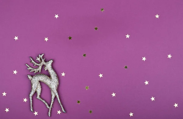 Shiny gold deer ornament and gold stars, with copy space, on a purple background. the Christmas symbol is a deer. deer team