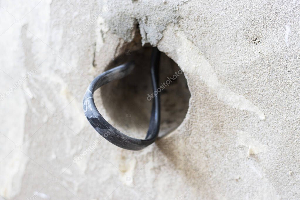 A hole in the plastered wall for an electrical outlet with wires. the concept of repair