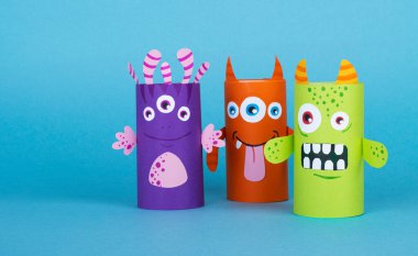 Mavi arka planda tuvalet kağıdından yapılmış renkli canavarlar. El yapımı. tekrar kullanım kavramı