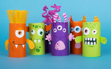 Mavi arka planda tuvalet kağıdından yapılmış renkli canavarlar. El yapımı. tekrar kullanım kavramı