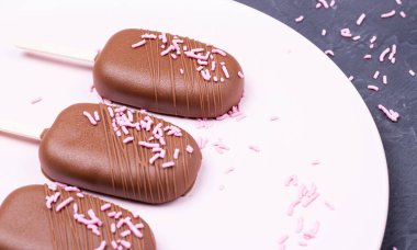 Tahta çubukta çikolatalı Eskimo dondurması. Tabakta çikolatalı dondurma.