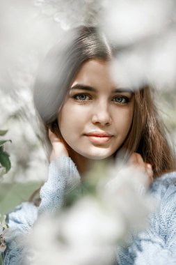 Çiçek açan bahçede mavi ceketli bir kız.