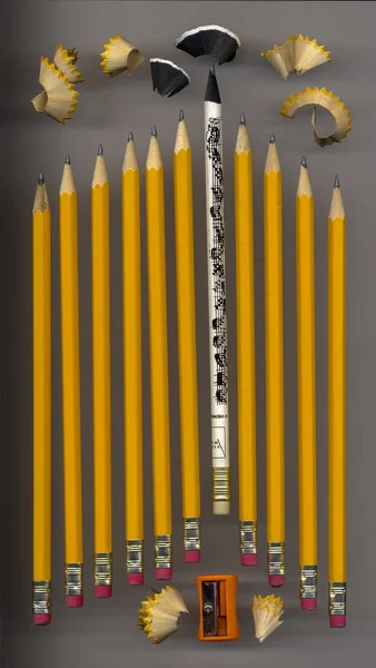 Sharpener and some sharp black pencils with pencil peels that are lying on a light background