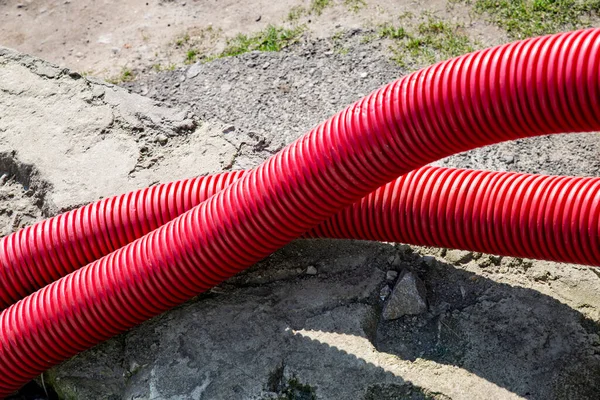 two plastic red pipes near the road on the construction