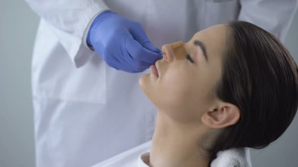 Žena spokojena s výsledkem operace nosu, cute usmívající se tvář odráží v zrcadle — Stock video