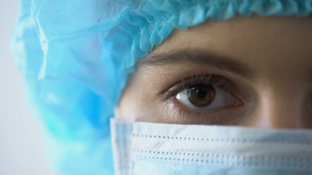 Femmina chirurgo in maschera in posa per la fotocamera, sguardo fiducioso del medico professionista — Video Stock