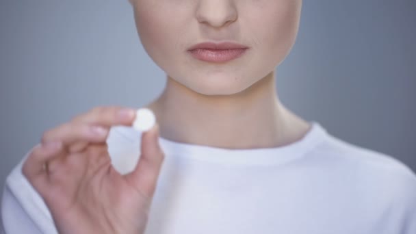 Молодая женщина принимает таблетки во рту, показывая на языке, добавки, витамины — стоковое видео