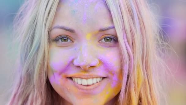 Menina brincalhão pintado em pó colorido sorrindo e posando para câmera, close-up — Vídeo de Stock