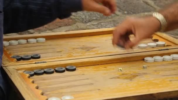 Пожилые пенсионеры играют в нарды во дворе снаружи, настольные игры — стоковое видео