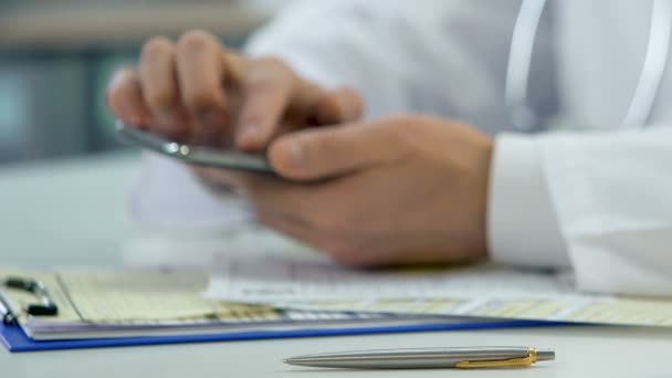 Manos de médico profesional desplazándose en el teléfono inteligente, consultando al paciente en línea — Vídeos de Stock