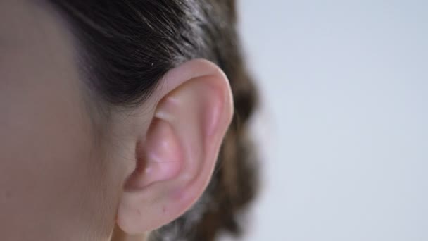 Медицинский работник устанавливает слуховой аппарат на ухо пациента, медицинское оборудование, устройство — стоковое видео