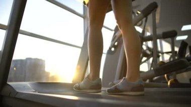 Kadın atlet bacaklarını yavaş yavaş yürüyüş koşu bandı makinesi, kardiyo egzersiz, dayanıklılık