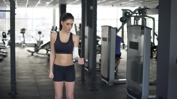 Mujer deportiva con el codo vendado levantamiento de pesas, la recuperación del cuerpo — Vídeos de Stock