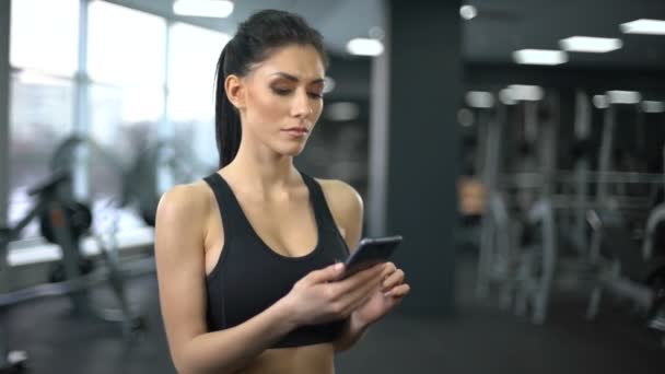 Doelgerichte dame in sportkleding scrollen smartphone toepassing, motivatie — Stockvideo