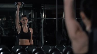 Kadın vücut geliştirmeci eğitim pazı ve omuz dumbbells ile egzersiz yapıyor,