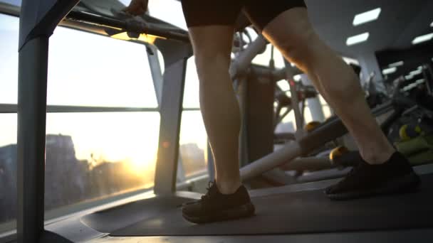 Atleet man loopt op de loopband in de sportschool, warming-up vóór de training, gezondheid — Stockvideo