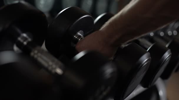 Gros plan de la main masculine prenant haltères, équipement de musculation dans la salle de gym — Video