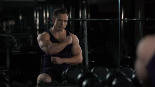 Bodybuilder tittar på sig själv i spegeln efter träningspass, nöjda med resultat — Stockvideo