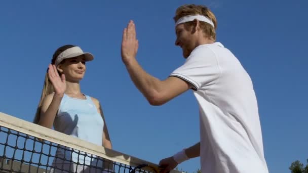 Happy young man and woman giving five over tennis net after match, slow-motion — Stok Video