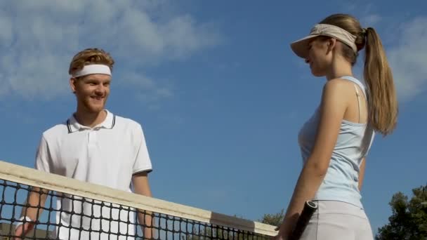 Unga par möte på tennisbana, handskakning efter spel, människor flirta — Stockvideo